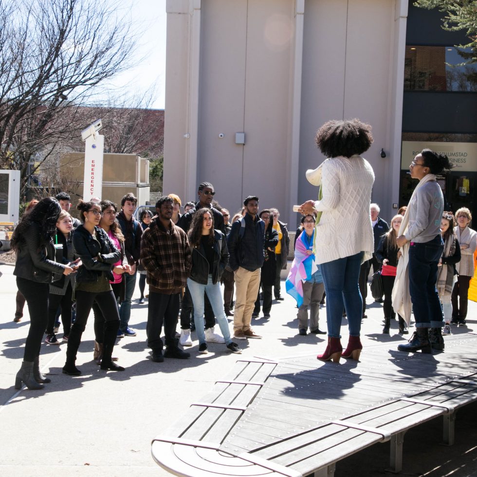 Adelphi student holding a bullhorn stands in front of a crowd