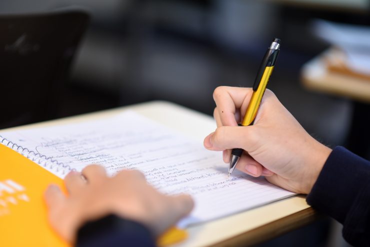 Close-up of someone writing notes with a yellow pen.