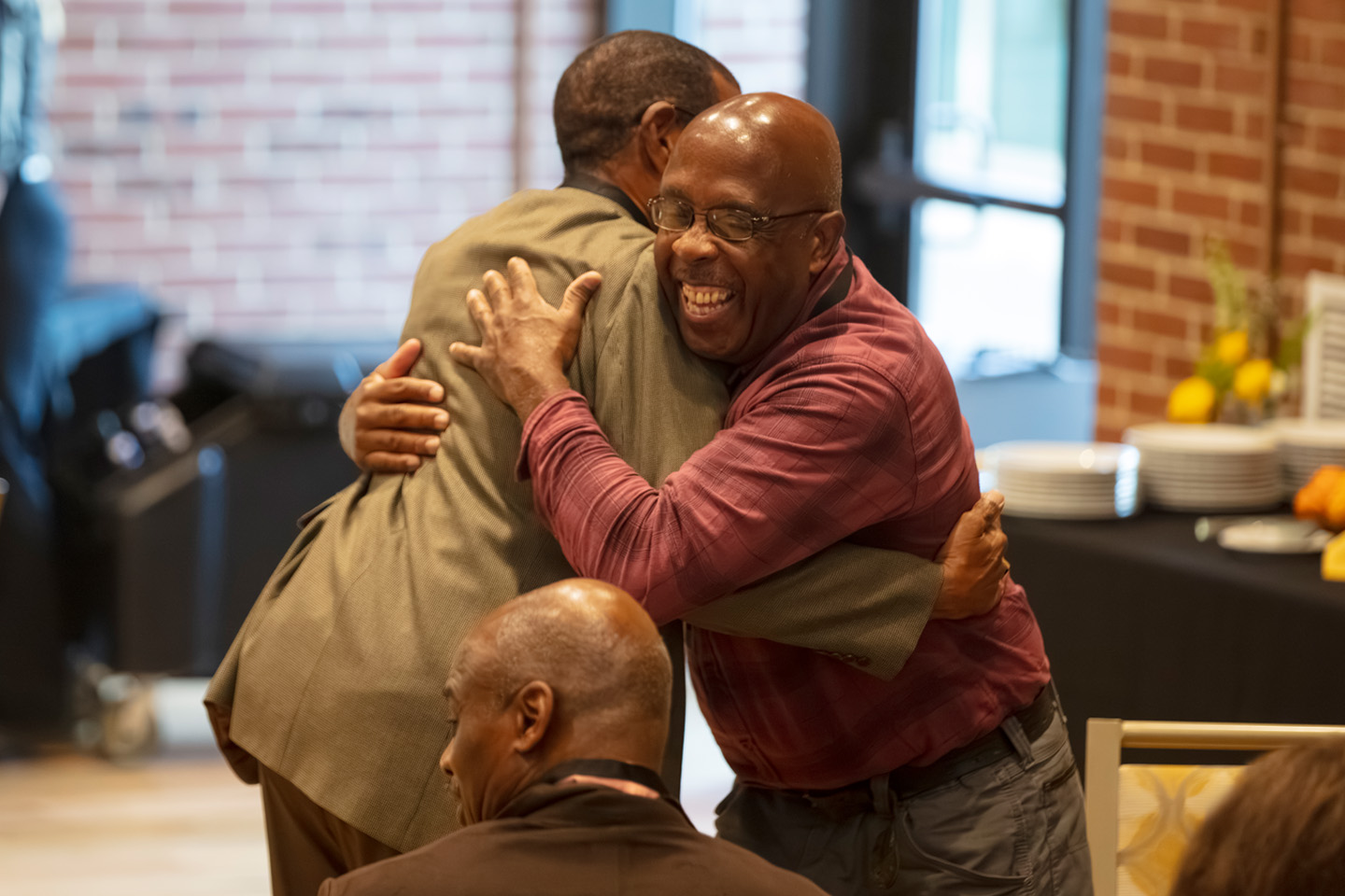 two alumni men hugging at a reunion at Adelphi.