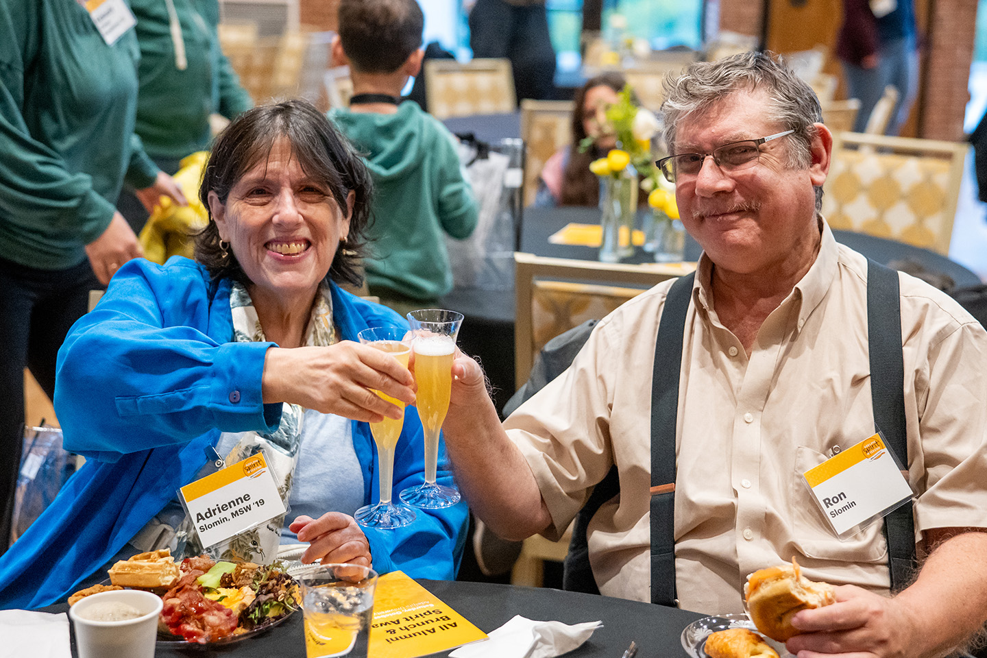A woman and man toast with glasses of beer at Oktoberfest.