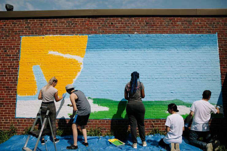 Adelphi student painting a mural