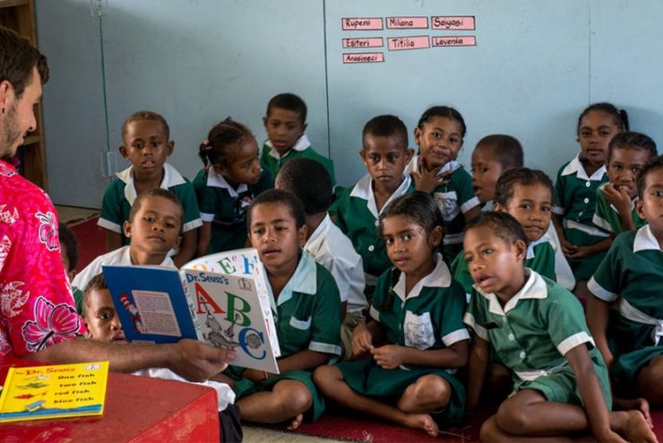 A student reading Dr. Seuss in English abroad to a room of children.