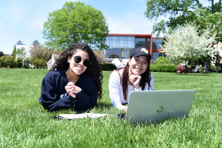 Two students study in the sunshine on the Adelphi campus lawn