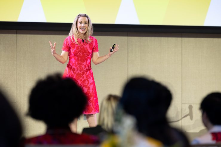 A row of women at the conference applaud a speaker.