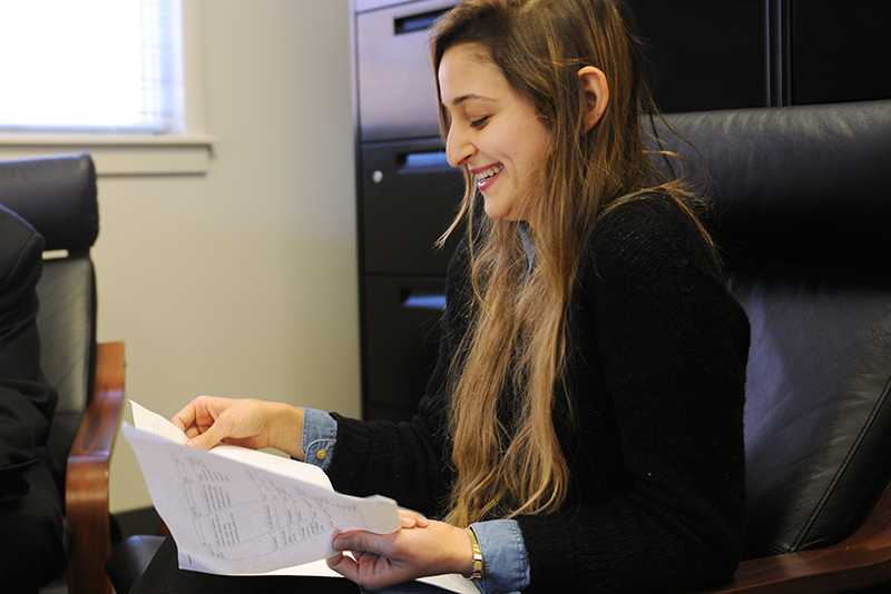Adelphi psychology student smiling while looking at papers