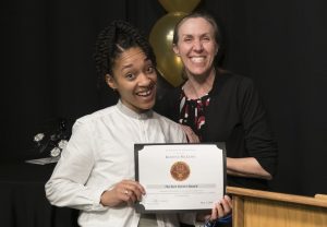 Student Kedine receives an award from the Communications Department.