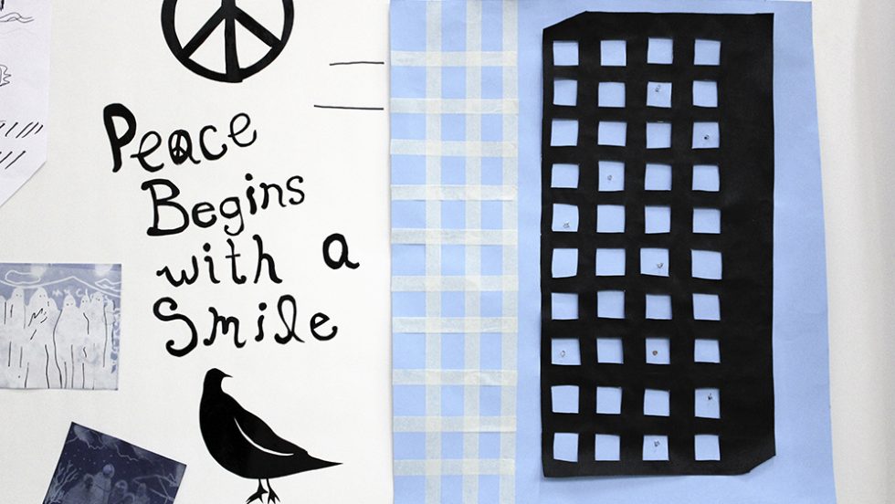 A peace symbol with a bird and building. Words read "Peace begins with a smile"