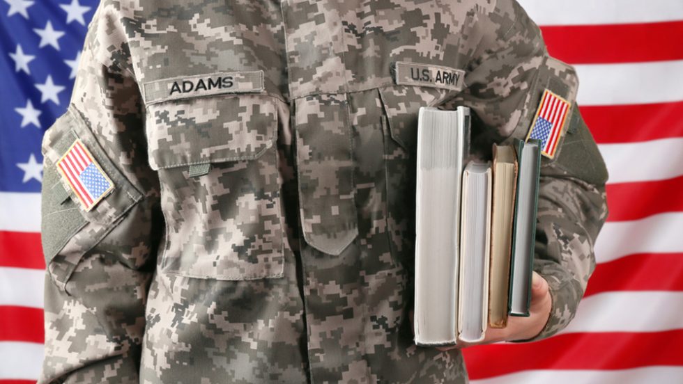 An Army member holding books in front of an American flag