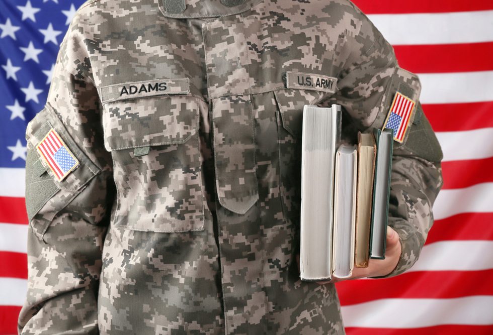 An Army member holding books in front of an American flag