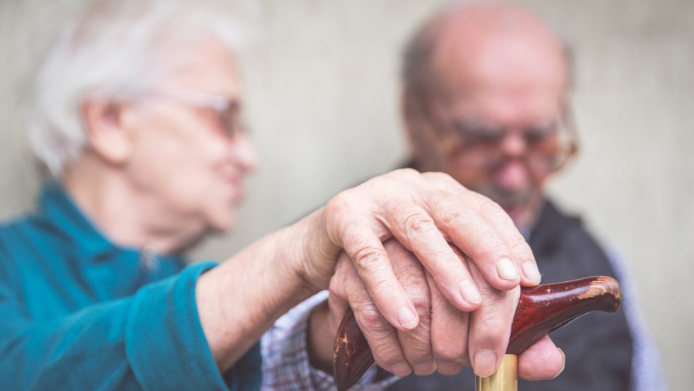 Two elderly people holding hands