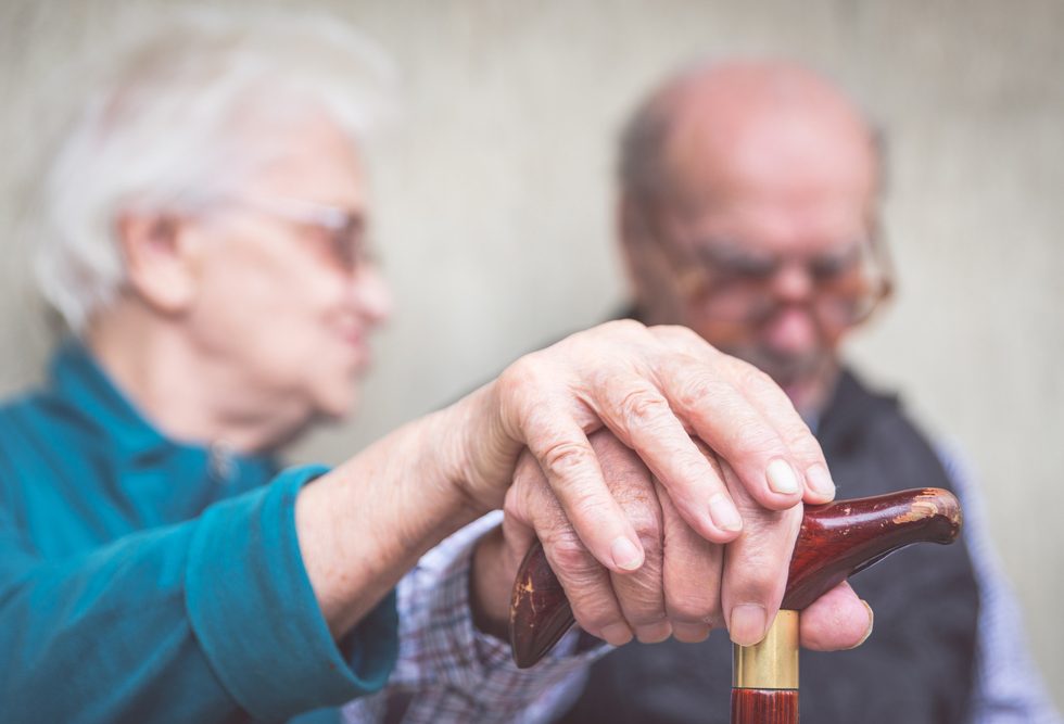 Two elderly people holding hands