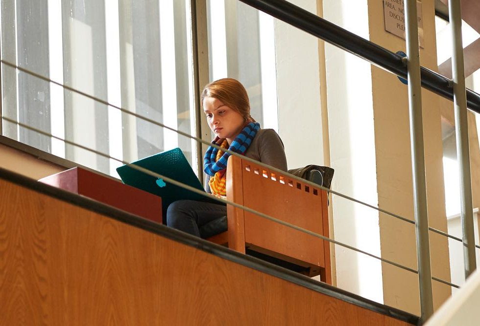 A student in the Swirbul Library using a laptop.