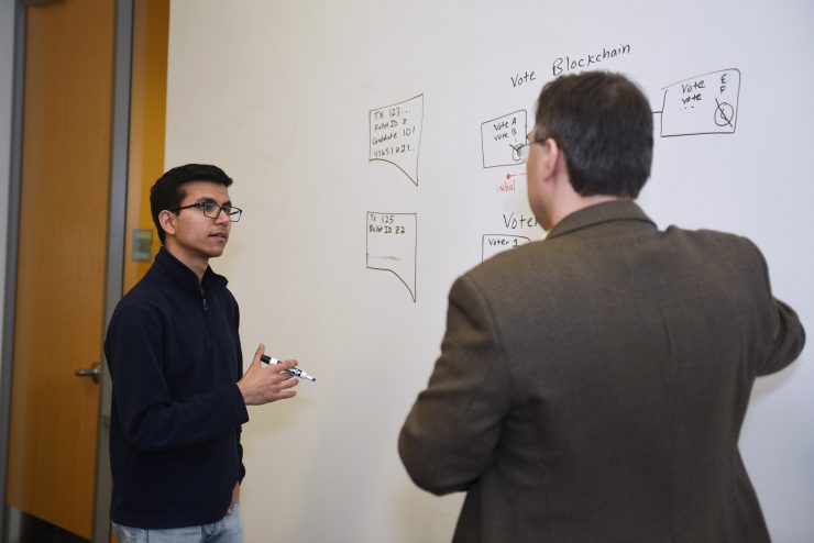 Student and professor standing at a whiteboard