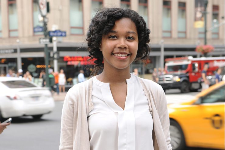 A young woman smiles at the camera in New York City.