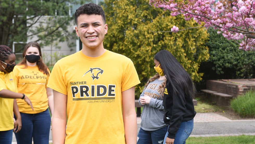 Miguel Velasquez in an Adelphi Pride Shirt outside on Adelphi's Campus