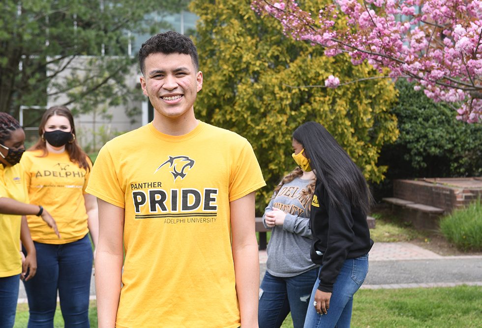 Miguel Velasquez in an Adelphi Pride Shirt outside on Adelphi's Campus