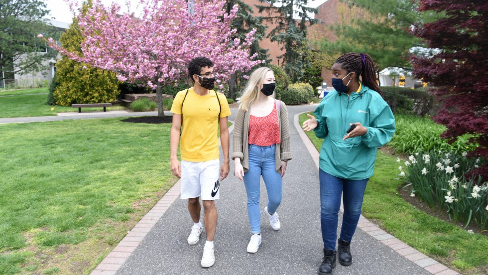 Students walking on campus wearing masks and being safe together.