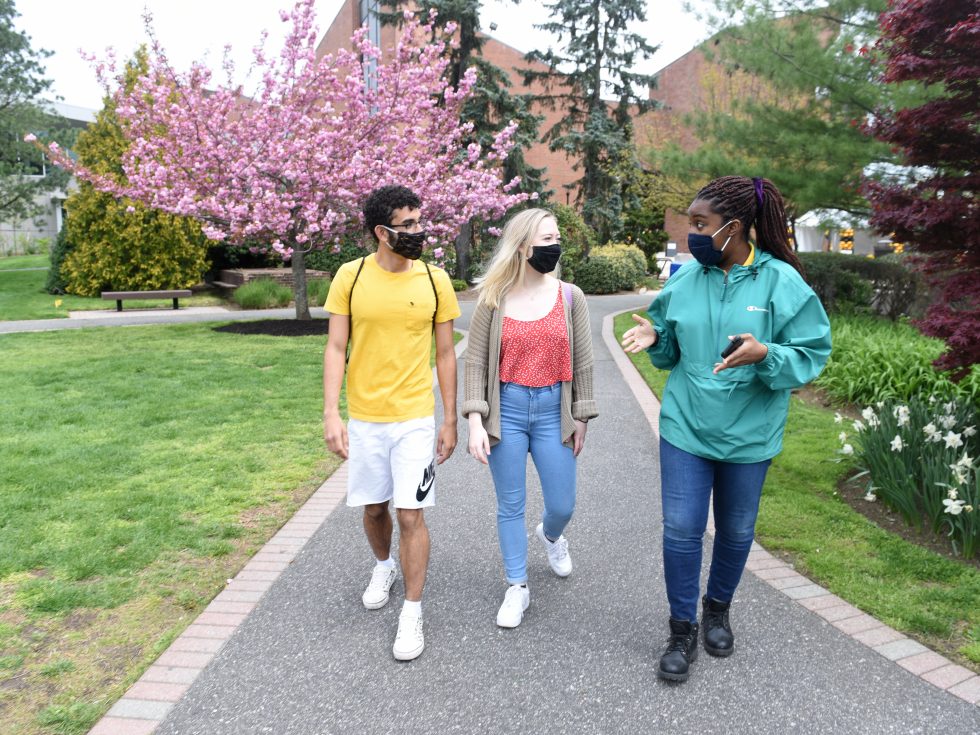 Students walking on campus wearing masks and being safe together.