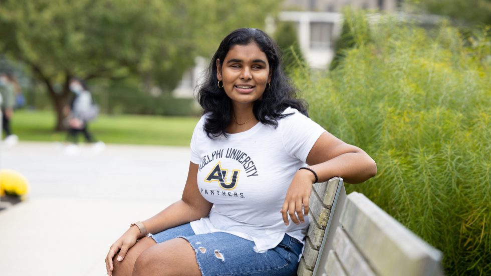 Jessica Karim sitting on a bench on Adelphi University's campus