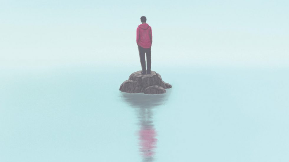 A photo of a person standing on a small patch of land with foggy water surrounding. 