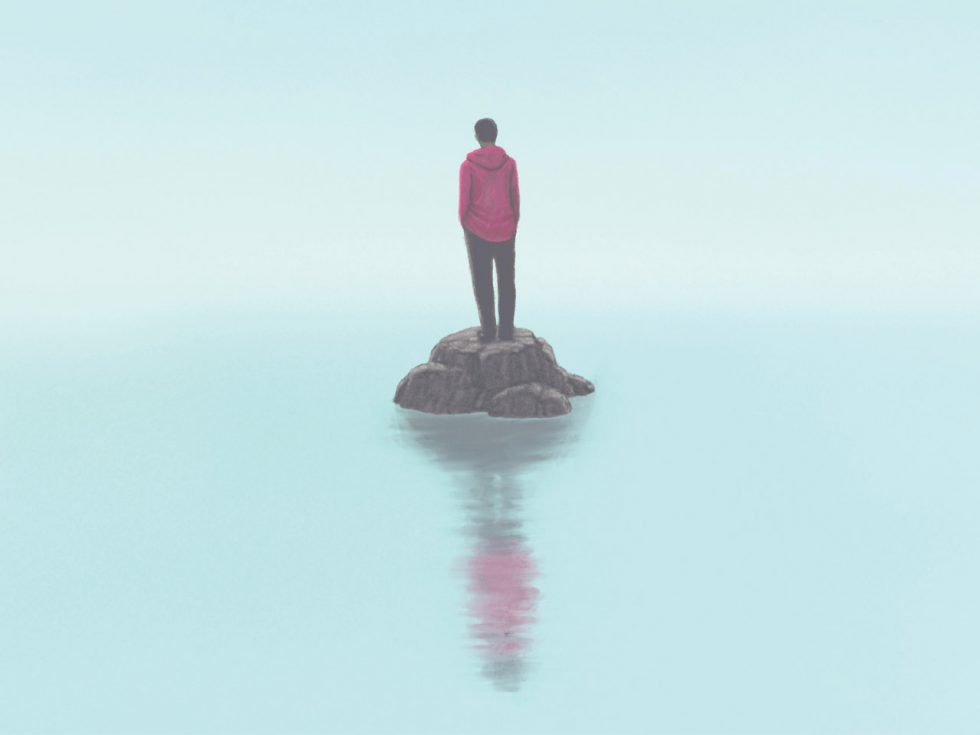 A photo of a person standing on a small patch of land with foggy water surrounding. 