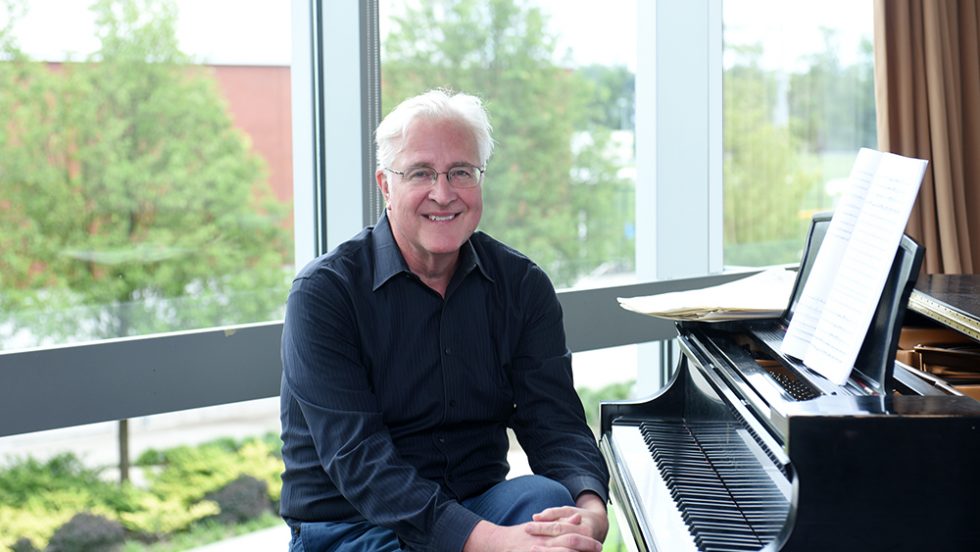 University Professor Paul Moravec, DMA pictured in front of a piano on Adelphi University's campus.