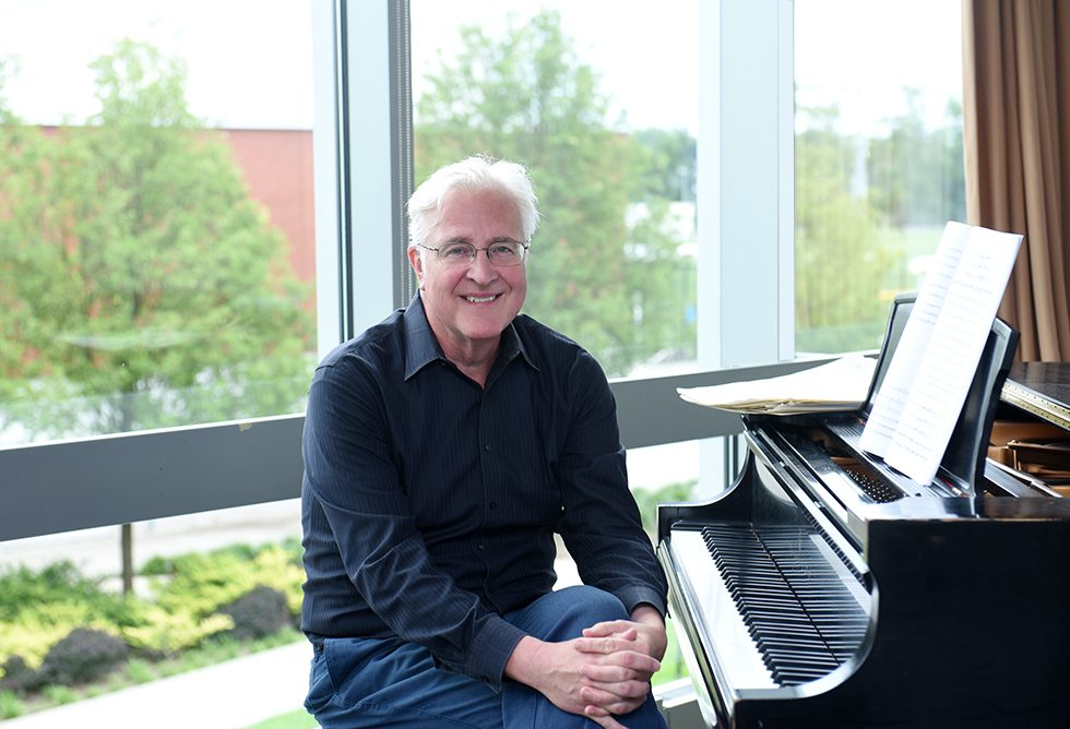 University Professor Paul Moravec, DMA pictured in front of a piano on Adelphi University's campus.