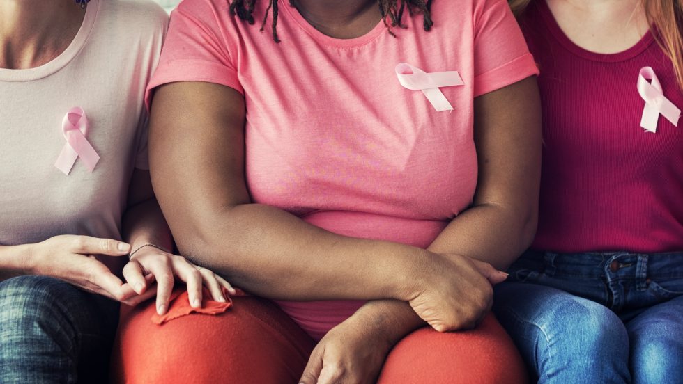 Women supporting each other wearing pink ribbons on their shirts.