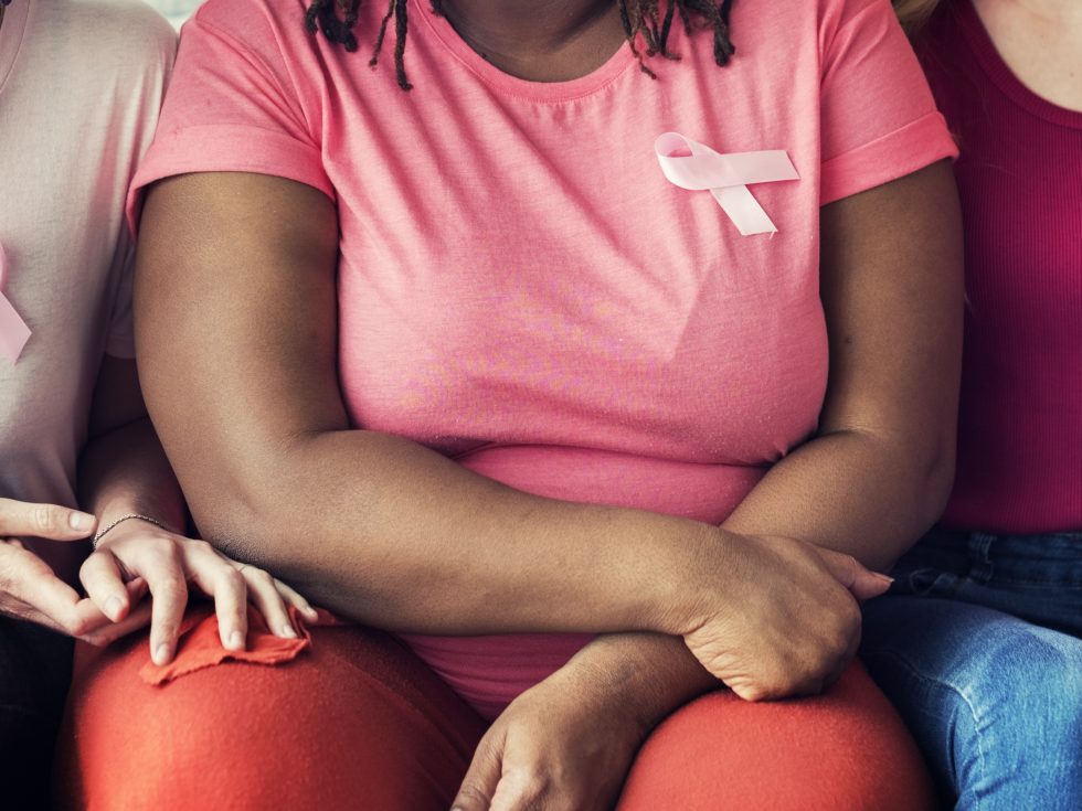 Women supporting each other wearing pink ribbons on their shirts.