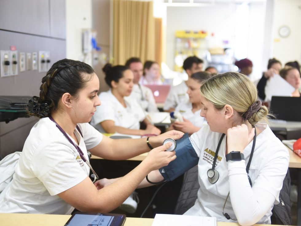 Adelphi nursing students taking blood pressure during class.