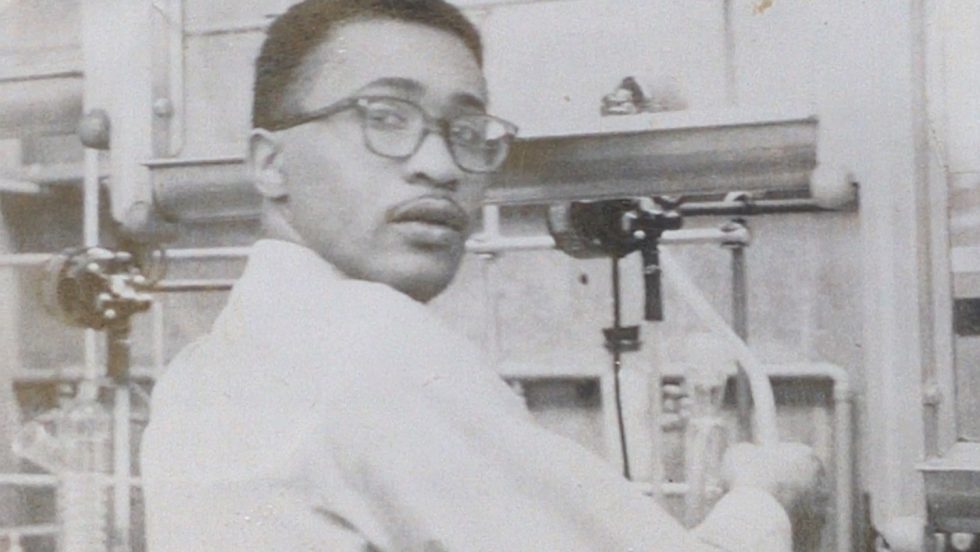 A black and white photo of Wesley Memeger as a young man working in a chemistry lab. 