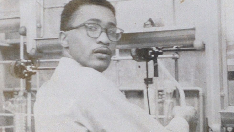 A black and white photo of Wesley Memeger as a young man working in a chemistry lab.