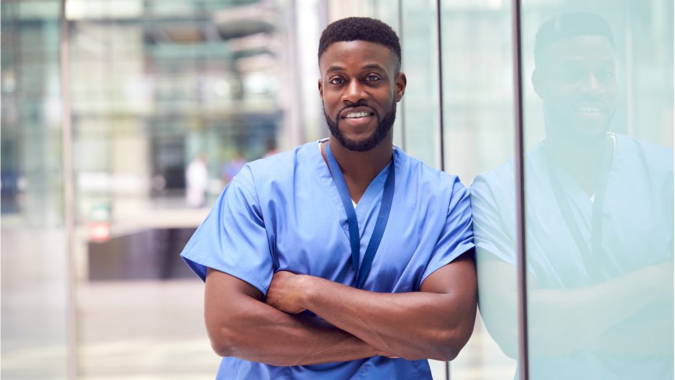 Male nurse leans against a glass wall