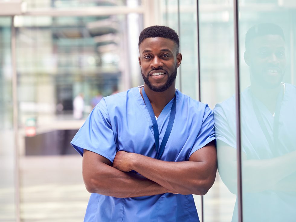 Male nurse leans against a glass wall