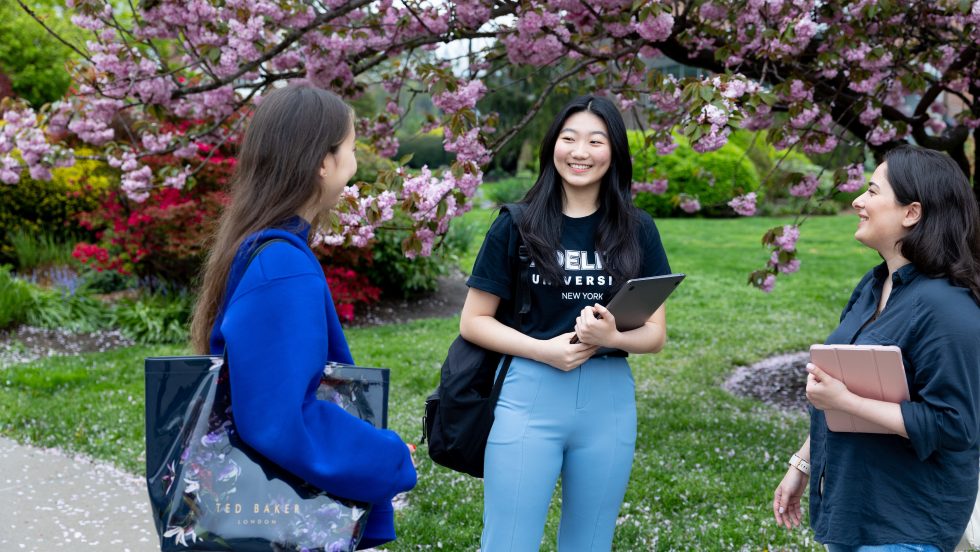 A group of Adelphi students on campus with cherry blossoms in the background