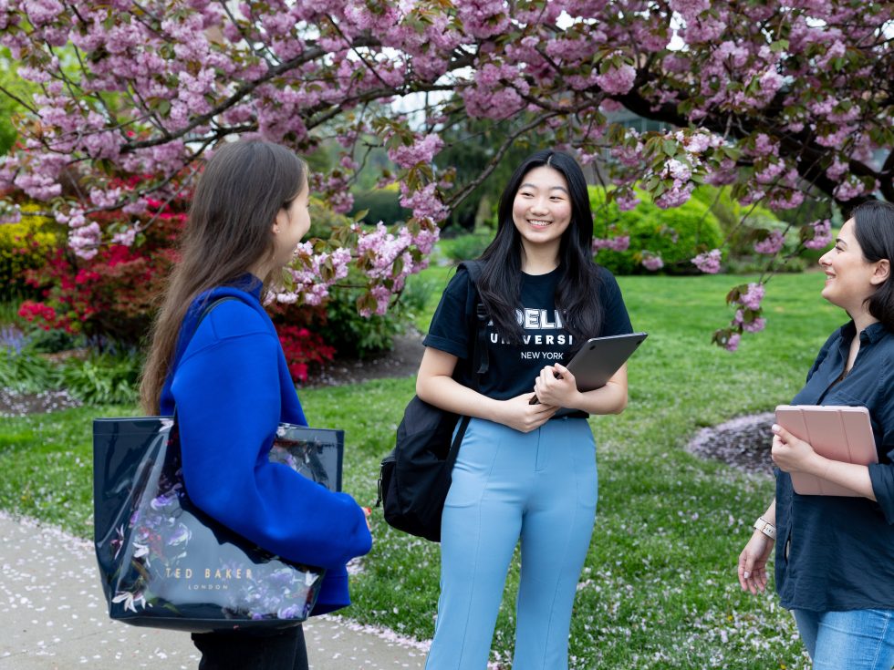 A group of Adelphi students on campus with cherry blossoms in the background