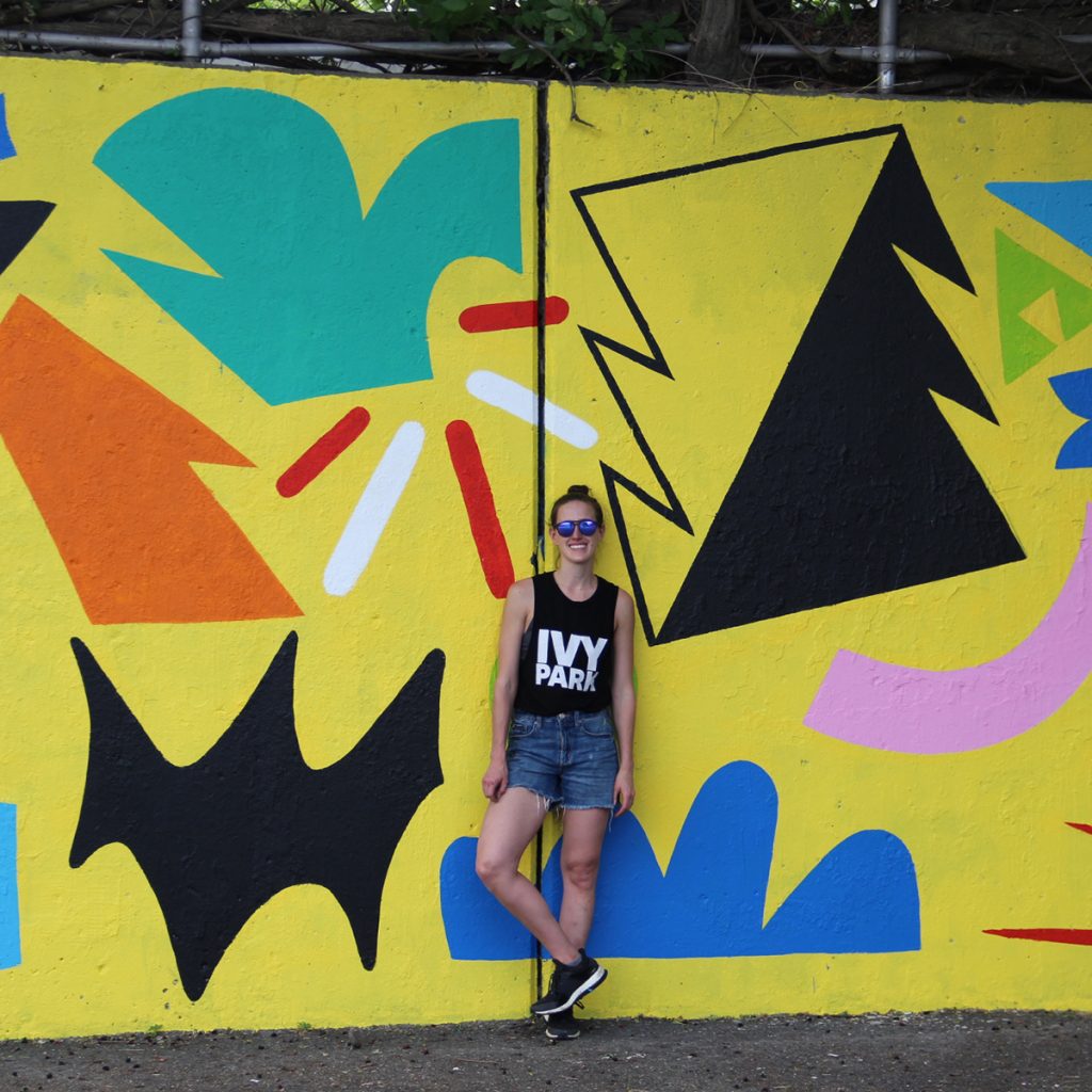  Brittany Baldwin '13 standing in front of one of her murals