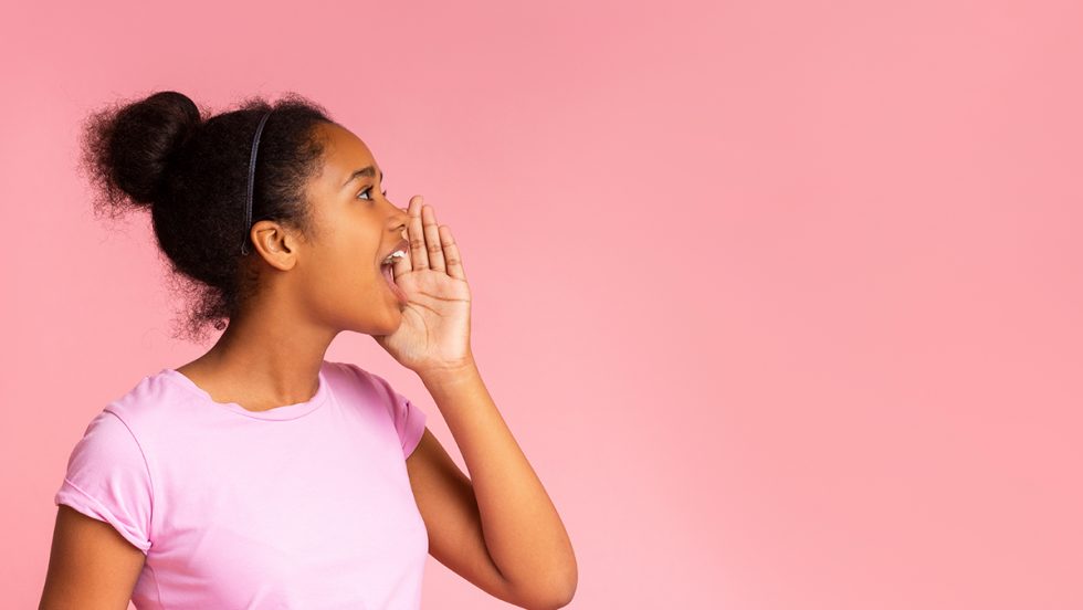 Young black girl shouting with a pink backdrop.