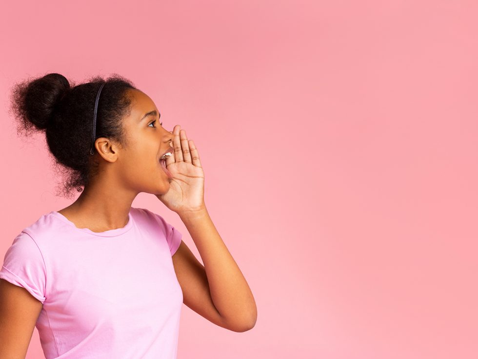 Young black girl shouting with a pink backdrop.