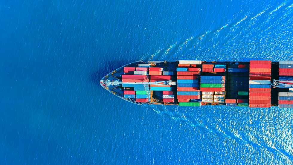 A cargo ship cutting through the water with shipping containers on deck