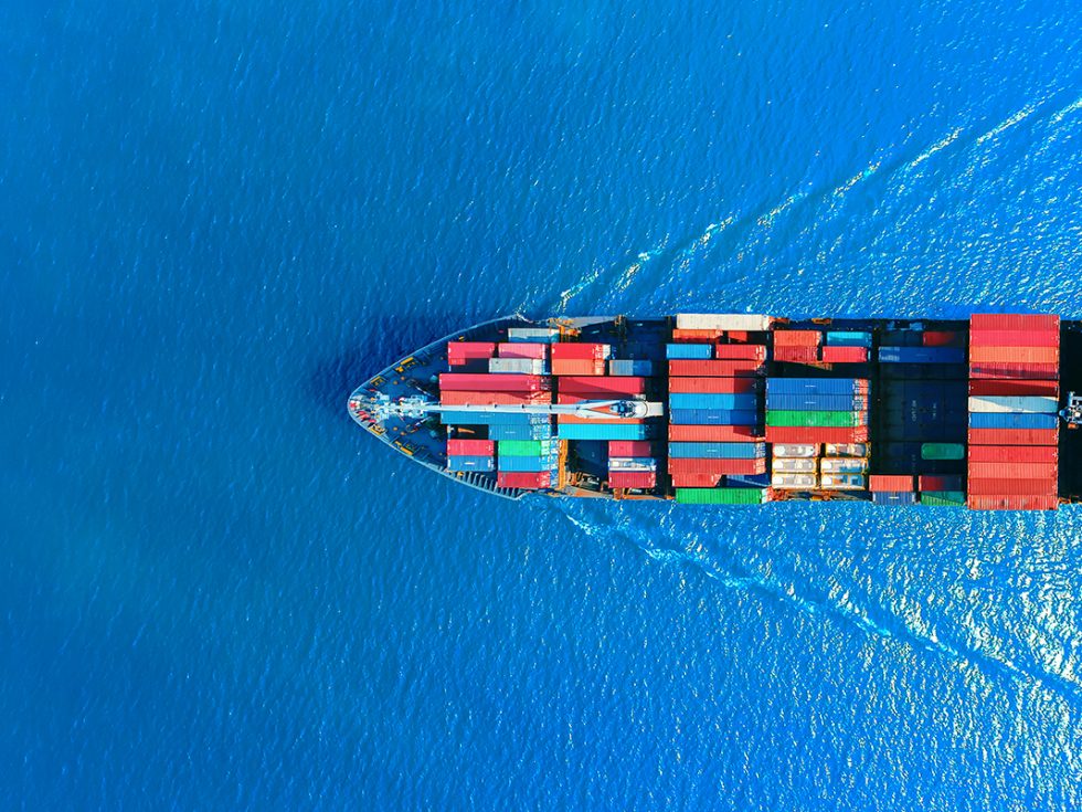 A cargo ship cutting through the water with shipping containers on deck