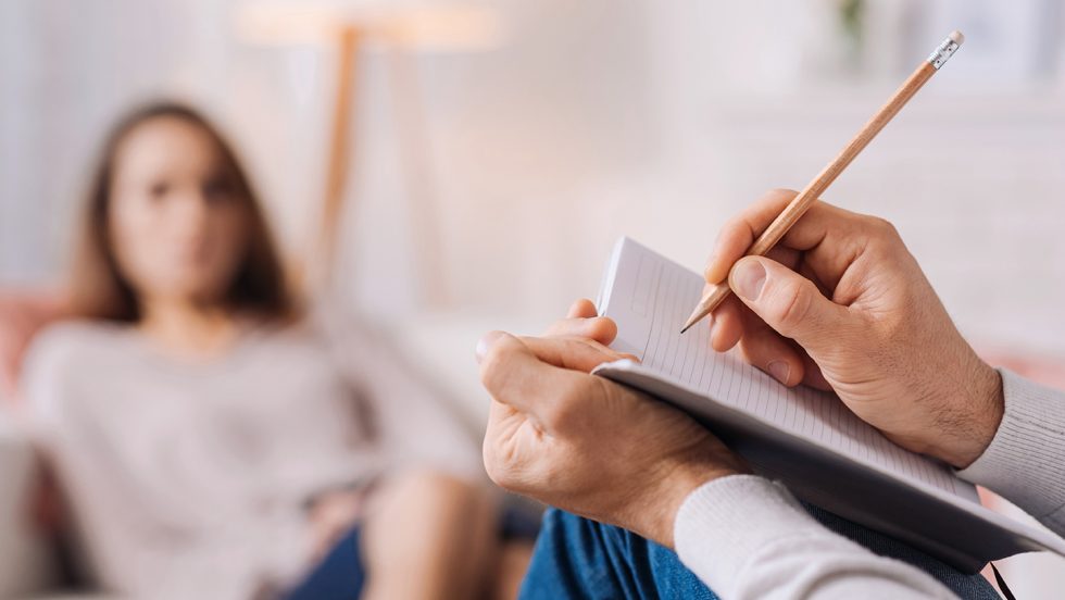 Therapist hands writing notes during a session with a patient