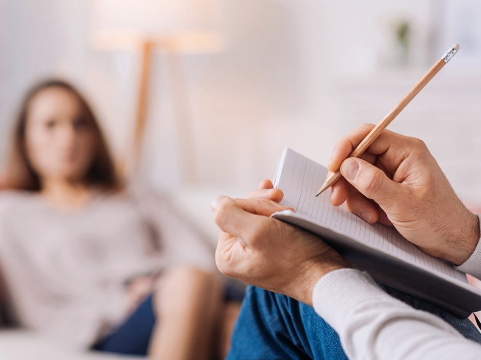 Therapist hands writing notes during a session with a patient