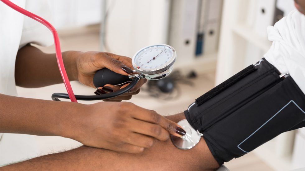 Blood pressure cuff placed on the arm of a black patient.