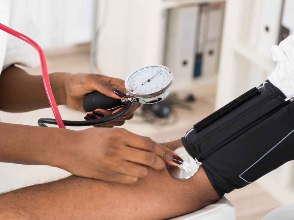 Blood pressure cuff placed on the arm of a black patient.