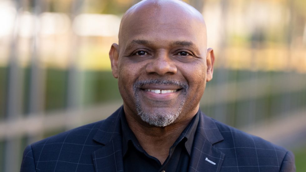 Telvis Rich standing in an outdoor area smiling at the camera.