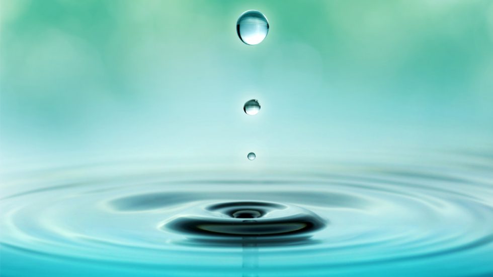 a water droplet falling into a relaxing, still pool of water