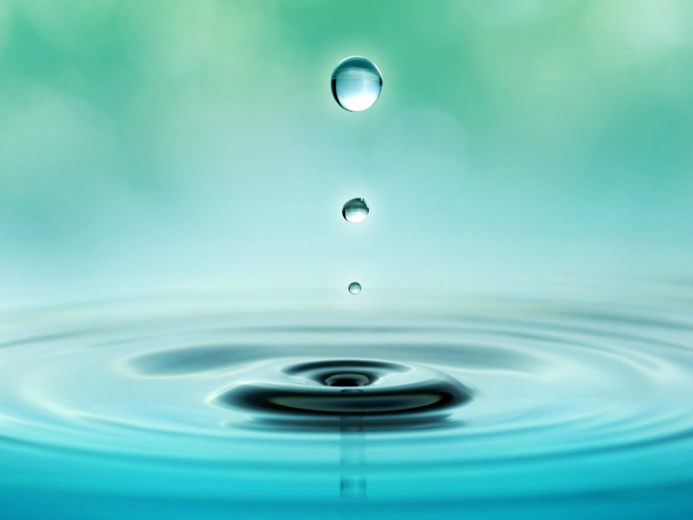 a water droplet falling into a relaxing, still pool of water