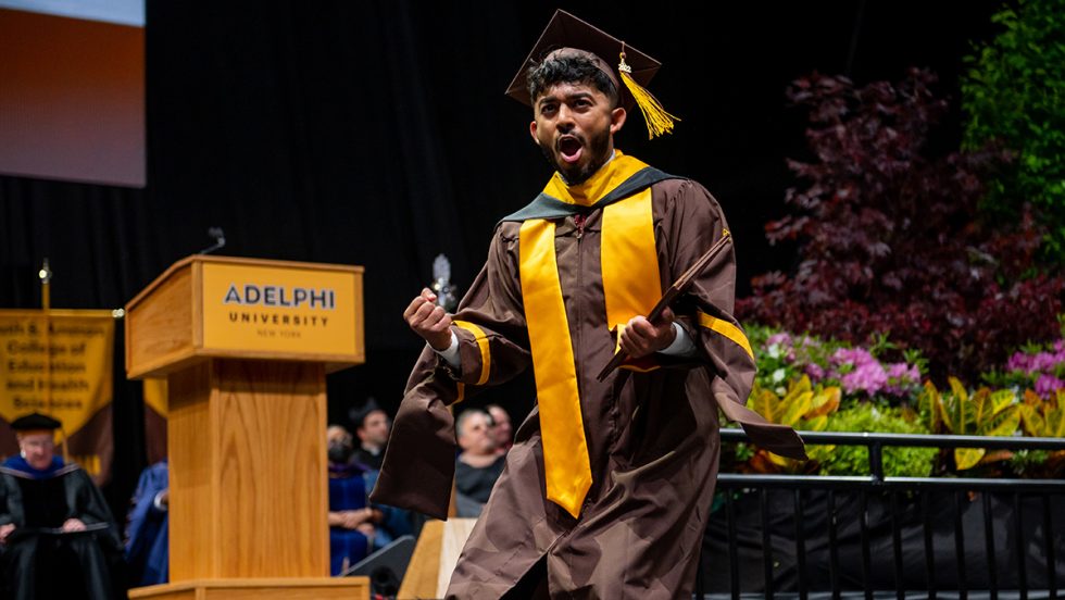 Adelphi University Commencement - an excited graduate celebrates earning their diploma on stage