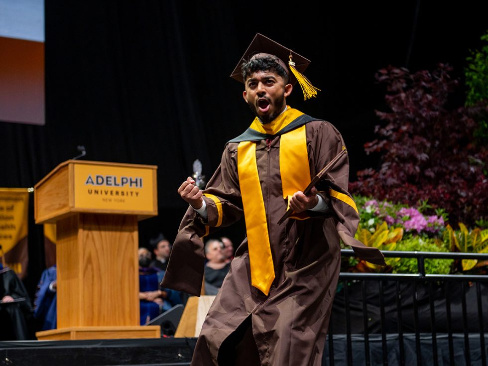 Adelphi University Commencement - an excited graduate celebrates earning their diploma on stage